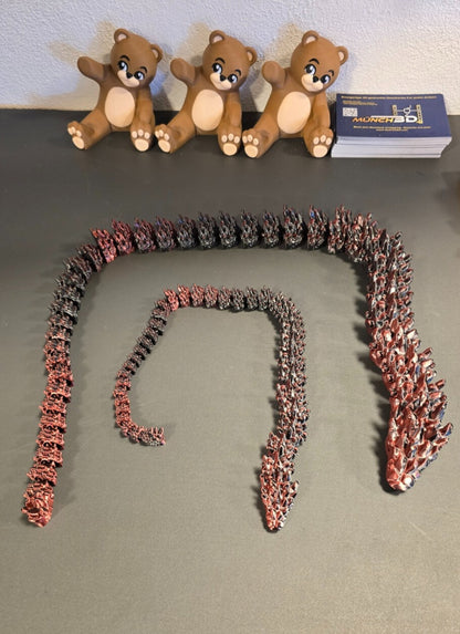 Große und kleine Drachen-Schlange nebeneinander auf Tisch

