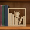 Baby-Drache Book-Nook-Buchstütze, sandfarbener 3D-Druck, zwischen echten Fantasy-Büchern in einem Holzregal, Frontalansicht