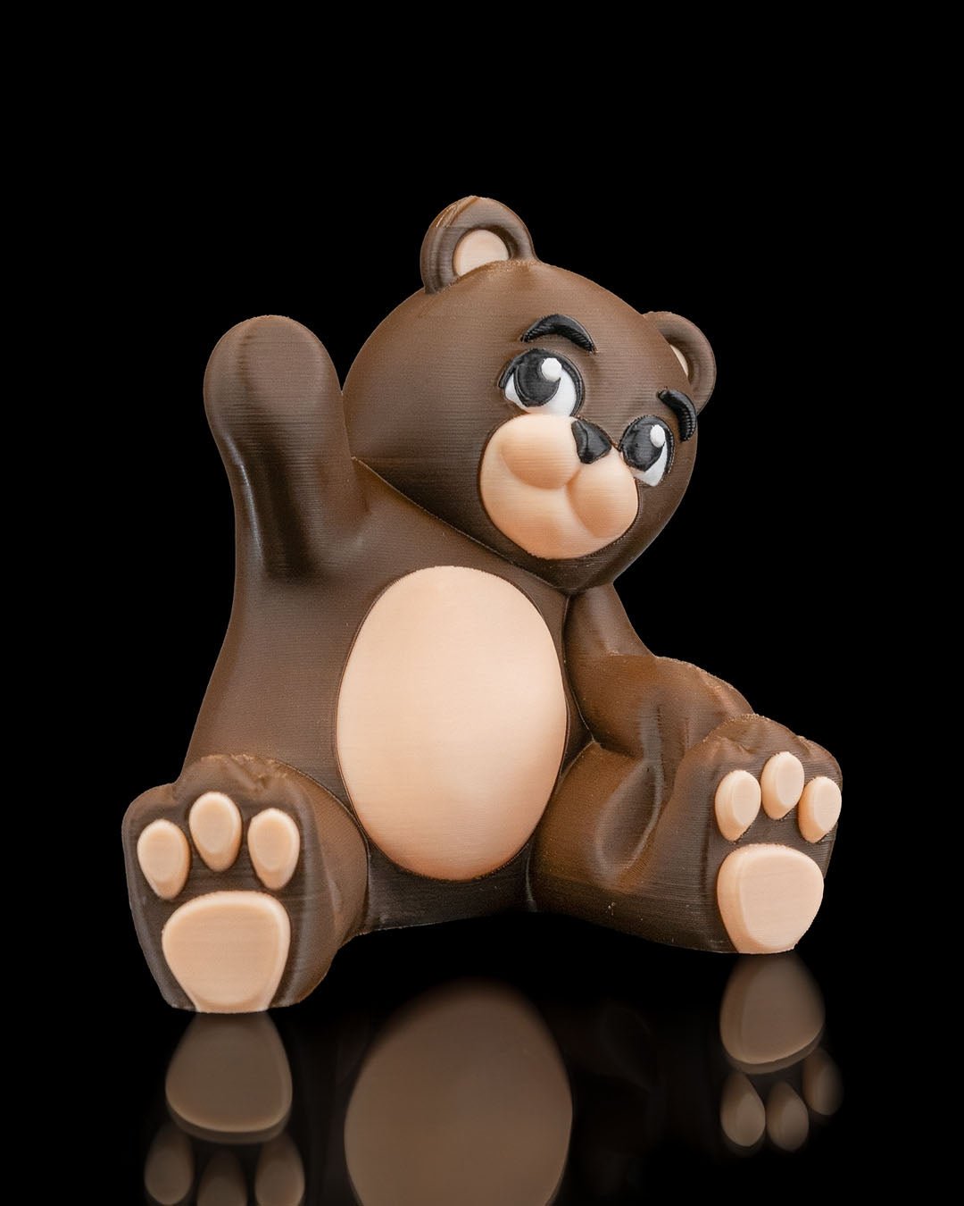Brauner Bären-Handyhalter ohne Smartphone, sitzende Figur mit erhobenem Arm, Frontalansicht vor schwarzem Hintergrund