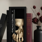Book Nook Totenkopf mit Skeletthand auf Wohnzimmer-Sideboard zwischen Büchern, Vase mit getrockneten roten Blüten im Hintergrund