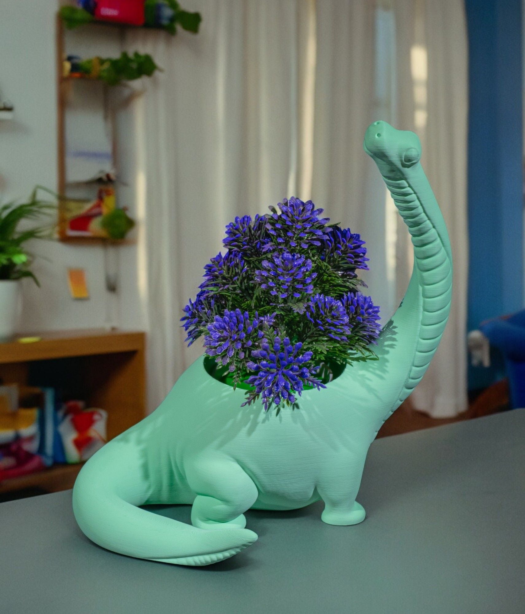 Mintgrüner Brachiosaurus-Blumentopf mit violettem Blütenstrauß auf einer Tischplatte, unscharfer bunter Wohnraum mit Vorhängen im Hintergrund