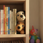 Book Nook Hundewelpen zwischen bunten Kinderbüchern im Kinderzimmerregal, weiches Nachmittagslicht, verschwommener Teddybär im Hintergrund