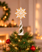 Christbaumspitze mit weiß-goldenem Stern und weißer Spirale auf einem Weihnachtsbaum mit Lichterkette sowie roten und goldenen Kugeln, warmes Zimmer mit Girlande im Hintergrund