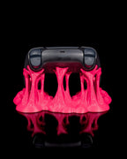 Schwarzer Gaming-Controller von hinten in pinkfarbenem Sticky-Splash-Ständer, Rückseite mit Schultertasten sichtbar, vor schwarzem Hintergrund