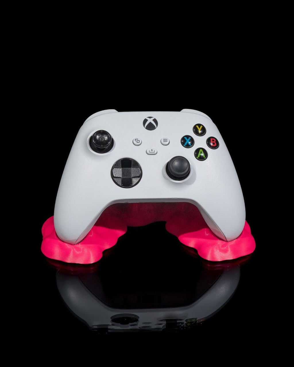 Weißer Gaming-Controller in pinkfarbenem Sticky-Splash-Controller-Ständer, Frontalansicht vor schwarzem Hintergrund