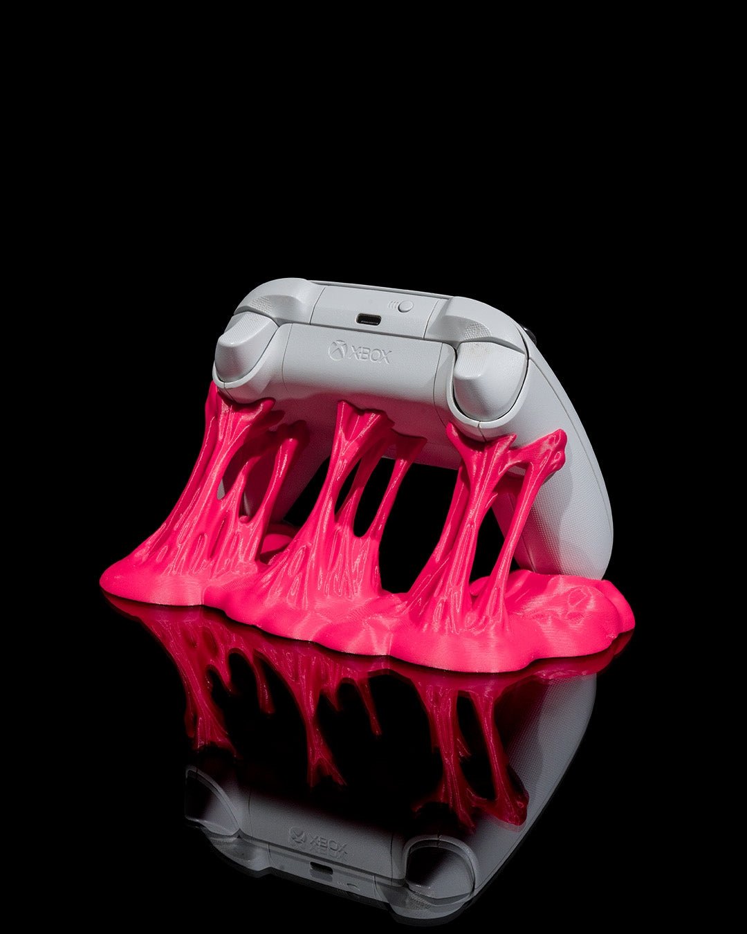 Weißer Gaming-Controller von hinten in pinkfarbenem Sticky-Splash-Ständer, Rückseite mit Schultertasten sichtbar, vor schwarzem Hintergrund