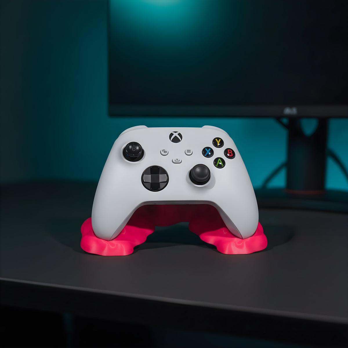 Weißer Gaming-Controller in pinkfarbenem Sticky-Splash-Controller-Ständer auf anthrazitfarbenem Gaming-Schreibtisch, zweiter Monitor mit türkisem Glanz im Hintergrund