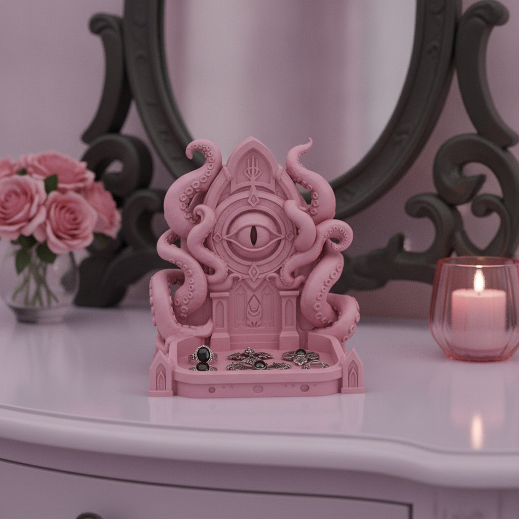 Rosa Cthulhu-Schmuckschale mit Ringen und Fledermaus-Anhängern in der Schale, auf einem Frisiertisch vor einem verzierten Spiegel mit Rosen