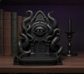 Schwarze Cthulhu-Schmuckschale mit Tentakeln und Auge, Frontalansicht auf einem Bücherregal neben alten Büchern und einem Kerzenständer