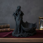 Gothic-Dämonin-Statue mit Flügeln, seitliche Ansicht mit Blick auf die geschwungene Schale und antiken Büchern im Hintergrund