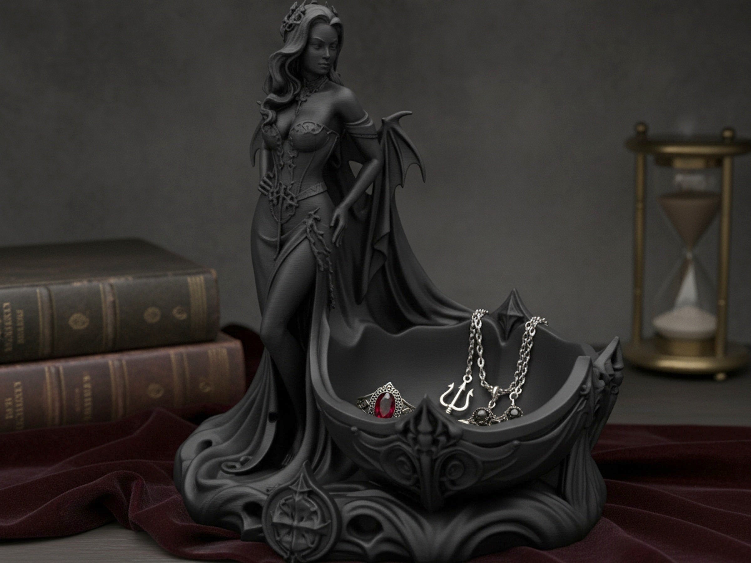 Gothic-Dämonin-Schalenstatue mit Schmuck darin: Ring, Kette mit Dreizack-Anhänger und Ohrringe, auf Bibliotheksregal mit Büchern und Sanduhr