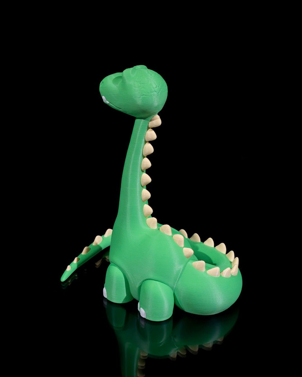 Grüner Dino-Handyhalter ohne Smartphone, seitliche Ansicht mit Stachelreihe entlang Hals und Rücken, schwarzer Hintergrund