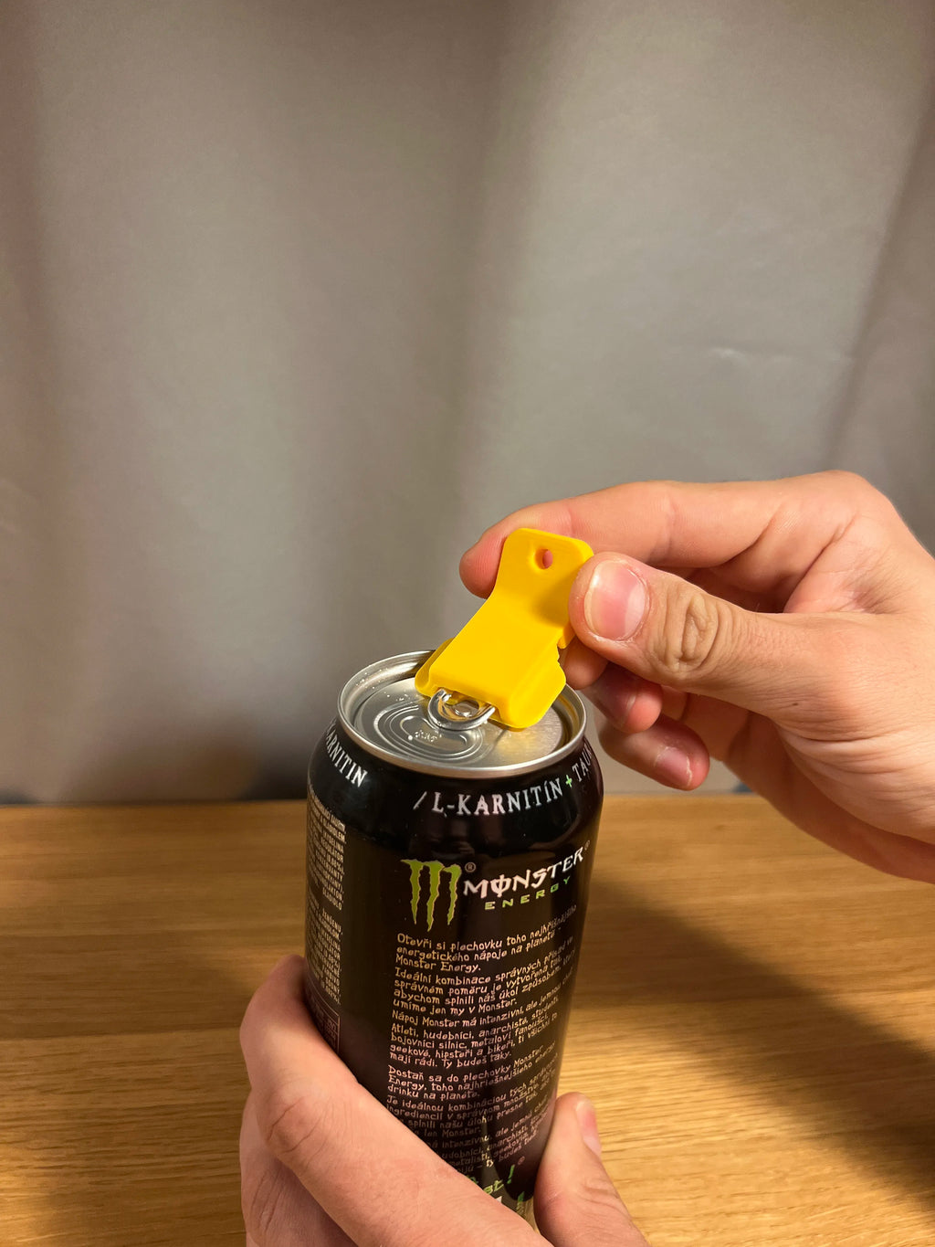 Gelber Dosenöffner-Clip hebelt die Aufreißlasche einer Energy-Drink-Dose in Großaufnahme auf