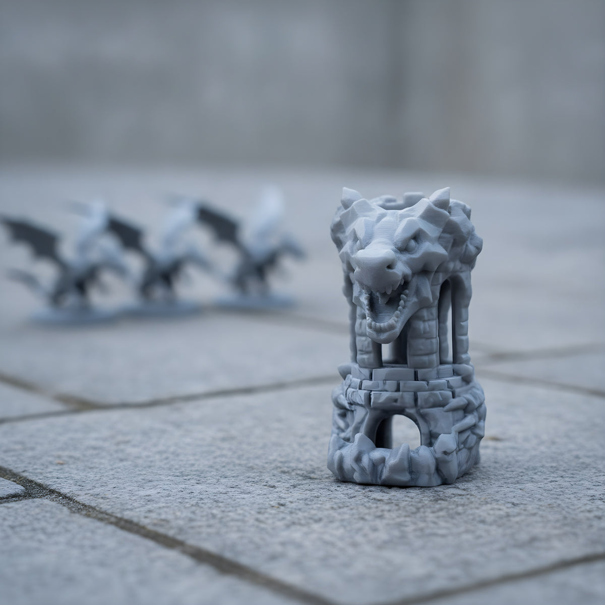 Drachen-Festungs-Würfelturm unbemalt in Silbergrau, Lieferzustand, auf verwitterter Steinplatte mit Drachen-Miniaturen im Hintergrund