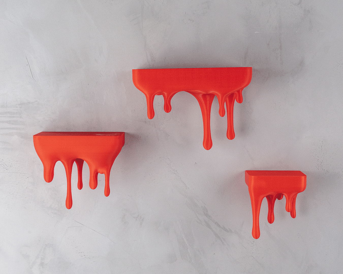 Drei Wandregale im Tropfen-Design in Rot-Orange, montiert an heller Steinwand, ohne Deko