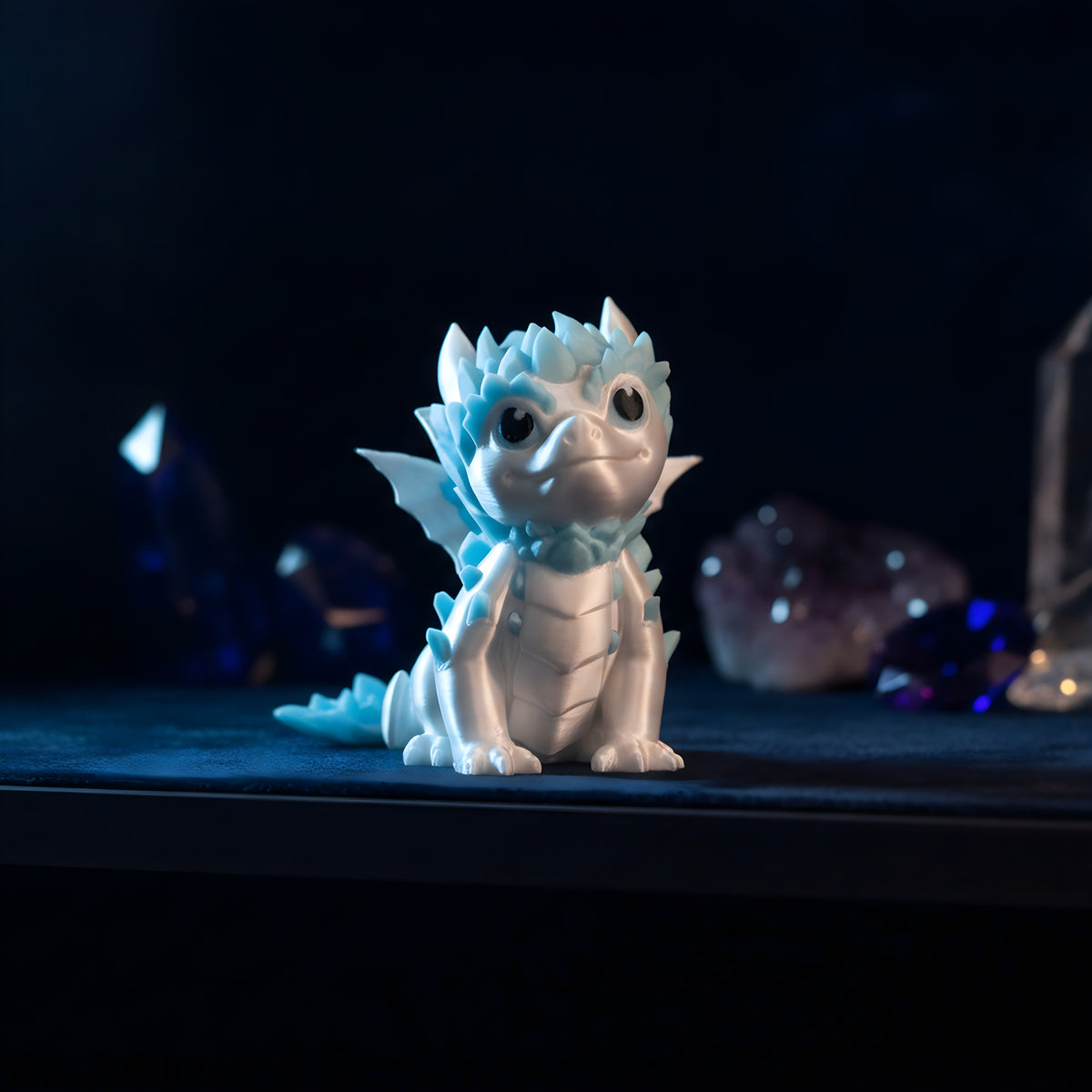 Weiß-blauer Eisdrache auf Kristallbasis, weitere Perspektive auf dunkelblauem Samt-Ausstellungsregal mit Kristall-Deko im Hintergrund – Münch3D