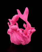 Detailansicht Fische-Skulptur in Pink: Yin-Yang-Fischmotiv der beiden ineinander verschlungenen Fische, vor schwarzem Hintergrund
