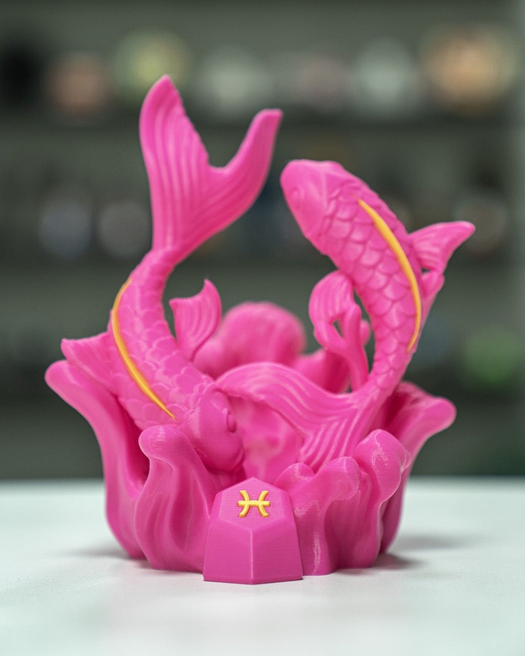 Fische-Sternzeichen-Skulptur in Pink mit goldenen Akzenten im Regal, unscharfer Hintergrund