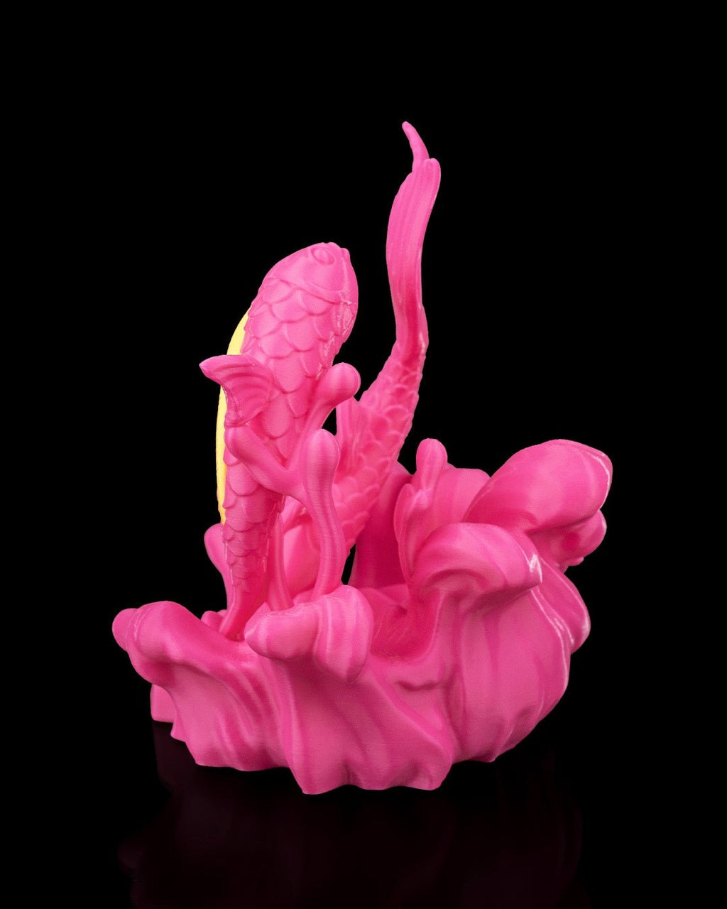 Nahaufnahme Fische-Sternzeichen-Figur in Pink: Schuppenstruktur und gelbe Bauchstreifen eines Fisches, vor schwarzem Hintergrund