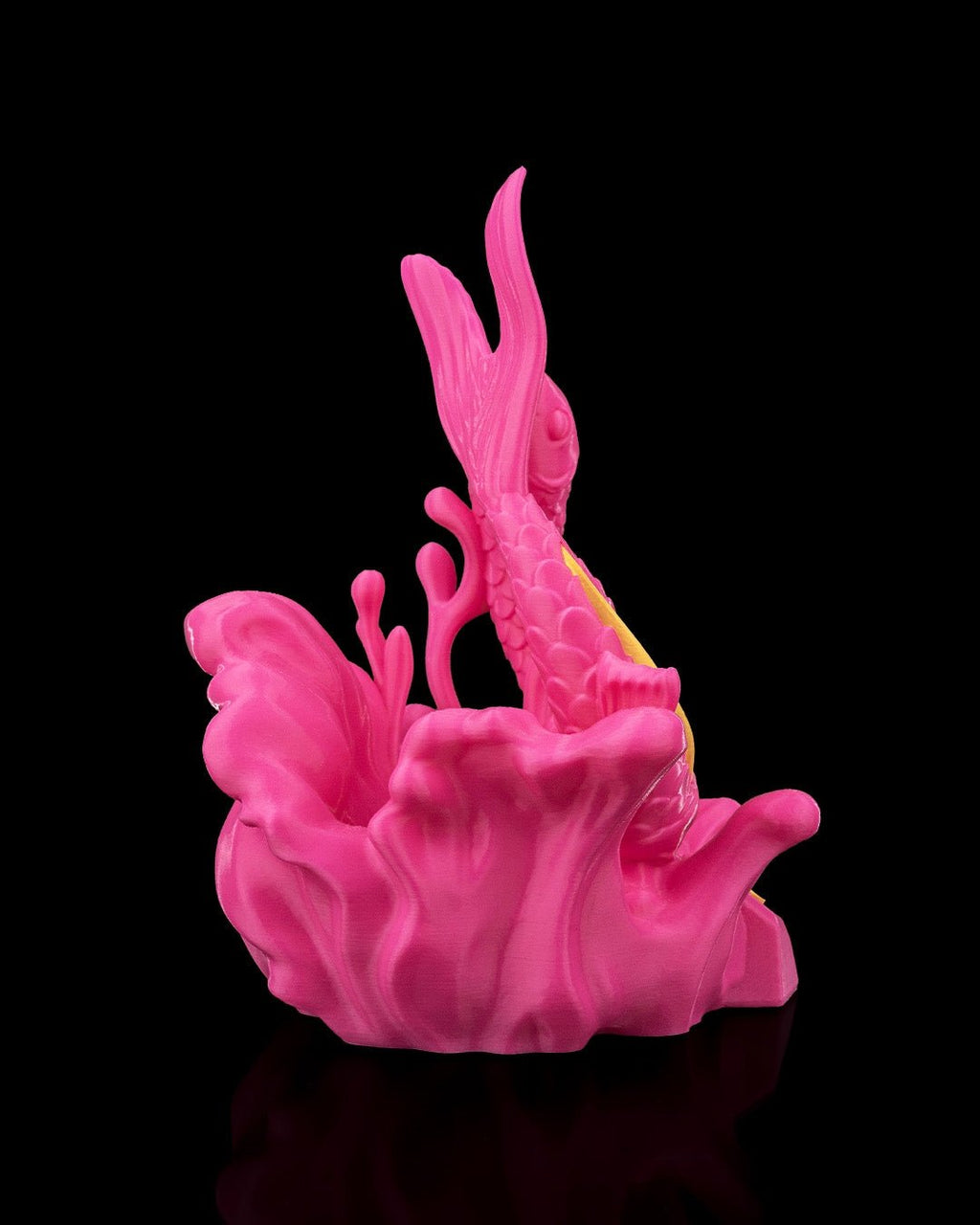 Fische-Sternzeichen-Skulptur in Pink aus erhöhter Perspektive mit Blick auf Fischkopf und Schwanzflosse, vor schwarzem Hintergrund