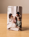 Foto-Kühlschrankmagnet mit Familienfoto (Mutter, Vater, Mädchen mit Häschen-Kuscheltier, Junge) auf Holztisch stehend