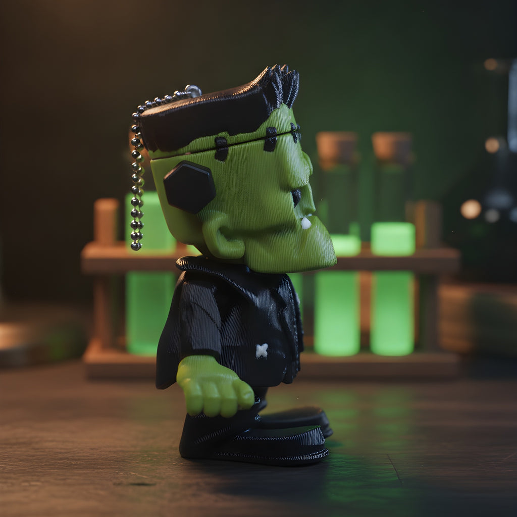 Frankenstein-Schlüsselanhänger seitlich fotografiert, im Hintergrund leuchtend grüne Glasfläschchen auf einem Holzregal.