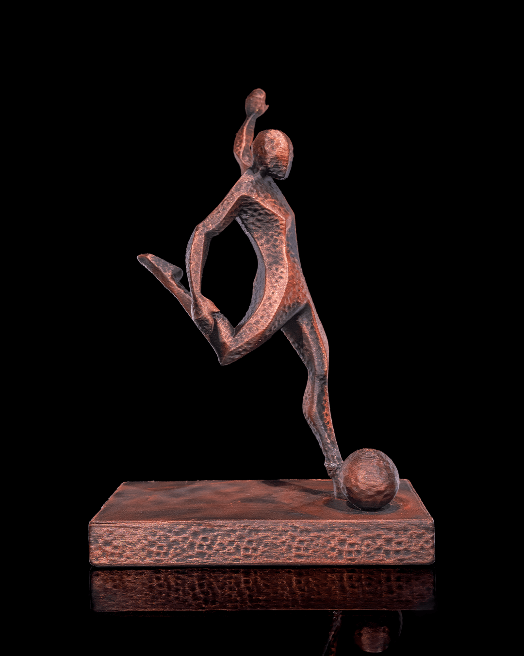 Fußballspieler-Statue in Kupfer-Optik, Seitenansicht mit Ball am Fuß vor schwarzem Hintergrund – Münch3D