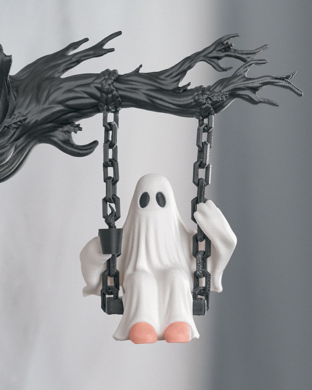Nahaufnahme der Geist-Figur auf der Kettenschaukel mit Tasse in der einen und Kette in der anderen Hand