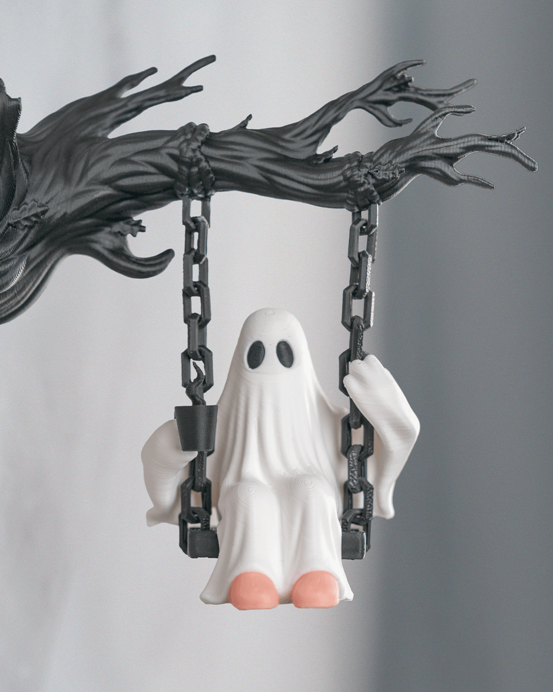 Nahaufnahme der Geist-Figur auf der Kettenschaukel mit Tasse in der einen und Kette in der anderen Hand