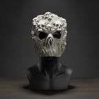 Ghoul-Totenkopf-Maske in Grau mit zahlreichen kleinen Schädeln auf der Oberfläche, auf schwarzer Ausstellungsbüste montiert, dunkler Studiohintergrund mit Spotlight