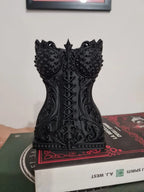 Echtes Foto des gedruckten Gothic-Korsett-Pinselhalters in Schwarz auf einem Bücherstapel