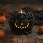 Gothic-Kuerbis-Teelichthalter mit LED-Teelicht im Kuerbismund, Halloween-Ambiente auf Holztisch mit Mini-Kuerbissen