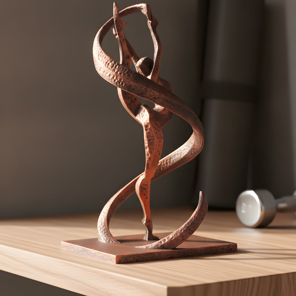 Gymnastik-Statue in Kupfer-Bronze-Optik auf Holzregal im Home-Gym, Dreiviertelansicht mit Bandwirbel, unscharfer Hintergrund mit Yogamatte und Kurzhantel – Münch3D