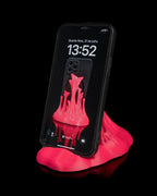 Neonpinker Splash-Handyhalter mit eingestecktem Smartphone, seitlich geneigte Ansicht vor schwarzem Hintergrund