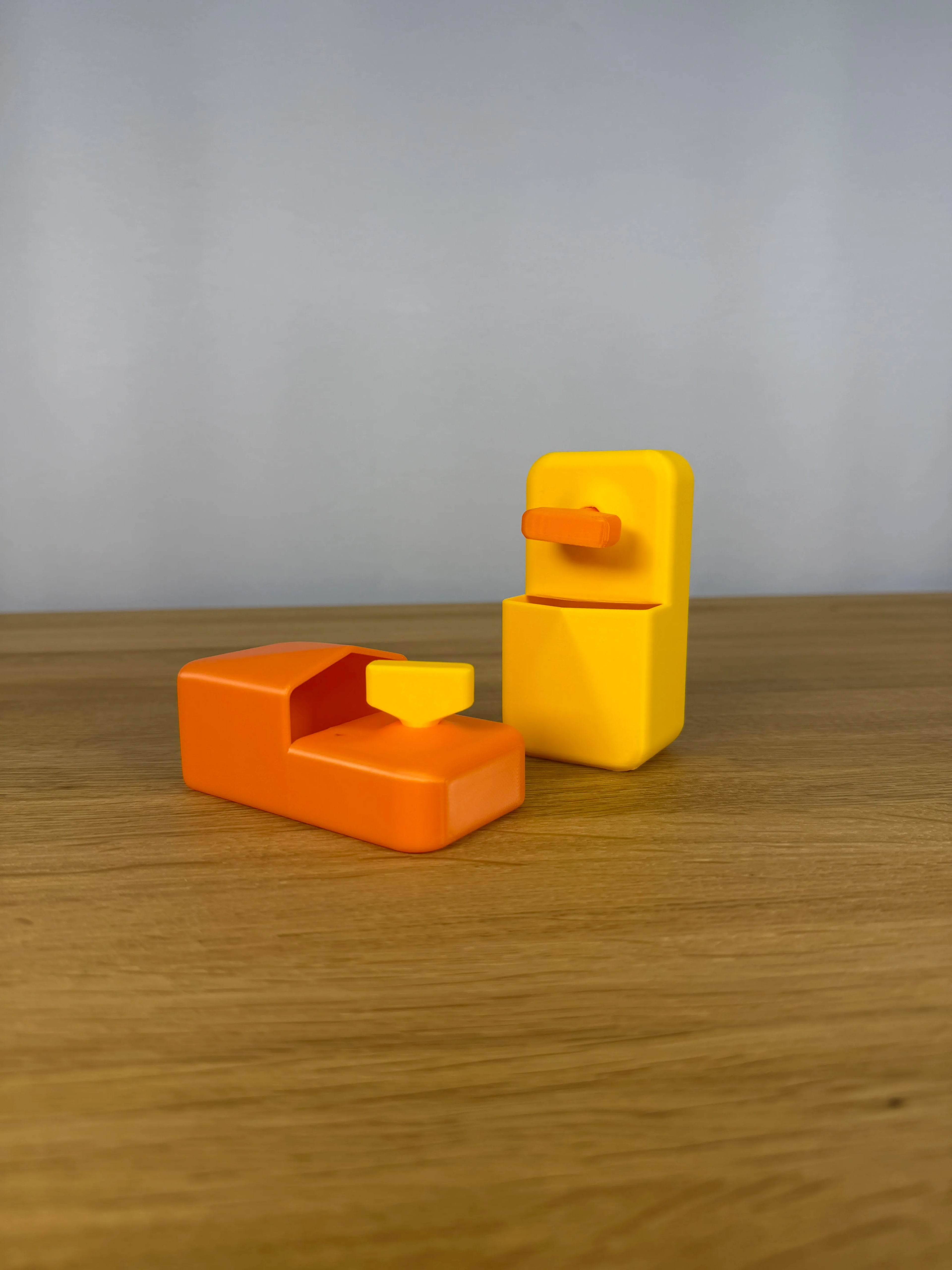Beide Farbkombinationen des Heizungsentlüfter-Schlüssel-Sets nebeneinander auf einem Holztisch, links Orange mit gelbem Schlüssel, rechts Gelb mit orangem Schlüssel