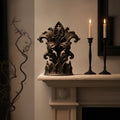 Gothic-Kathedralen-Skulptur mit Fleur-de-Lis-Blattranken in Mattschwarz auf einem hellen Kaminsims, daneben zwei schwarze Kerzenständer mit brennenden Kerzen
