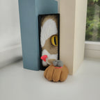 Katzen-Buchstütze mit Maus Book Nook auf weißem Fensterbrett zwischen zwei schlichten Büchern, Tageslicht und Blick ins Grüne im Hintergrund