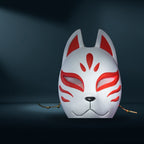Kitsune Maske Fuchs-Motiv in Weiß mit rotem Muster, Frontalansicht mit Schnurrhaar-Details vor dunklem Studiohintergrund