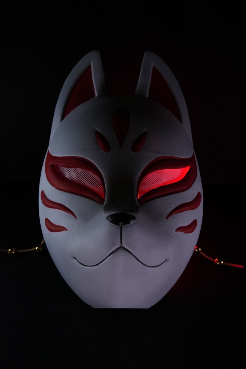 Kitsune Maske in Weiß mit rotem Fuchs-Muster, Frontalansicht in dunkler Umgebung mit rot beleuchteten Augenpartien – japanische Fuchs-Deko Münch3D (Bemaltes Fotomuster, Lieferung einfarbig)
