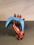 Kristallhand-Controllerhalter in Kupfer-Rot mit eingesetztem blauem Gaming-Controller, Frontalansicht vor Wohnzimmerwand