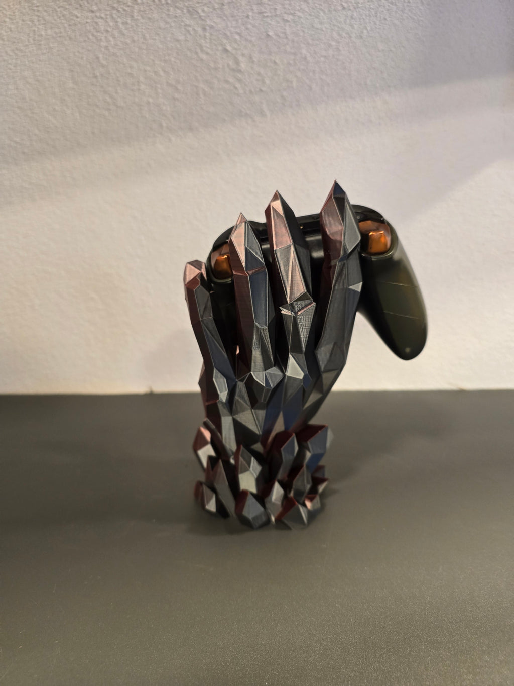 Kristallhand-Controllerhalter in Schwarz-Grau mit eingesetztem olivgrünem Gaming-Controller, Nahaufnahme von oben auf die Finger