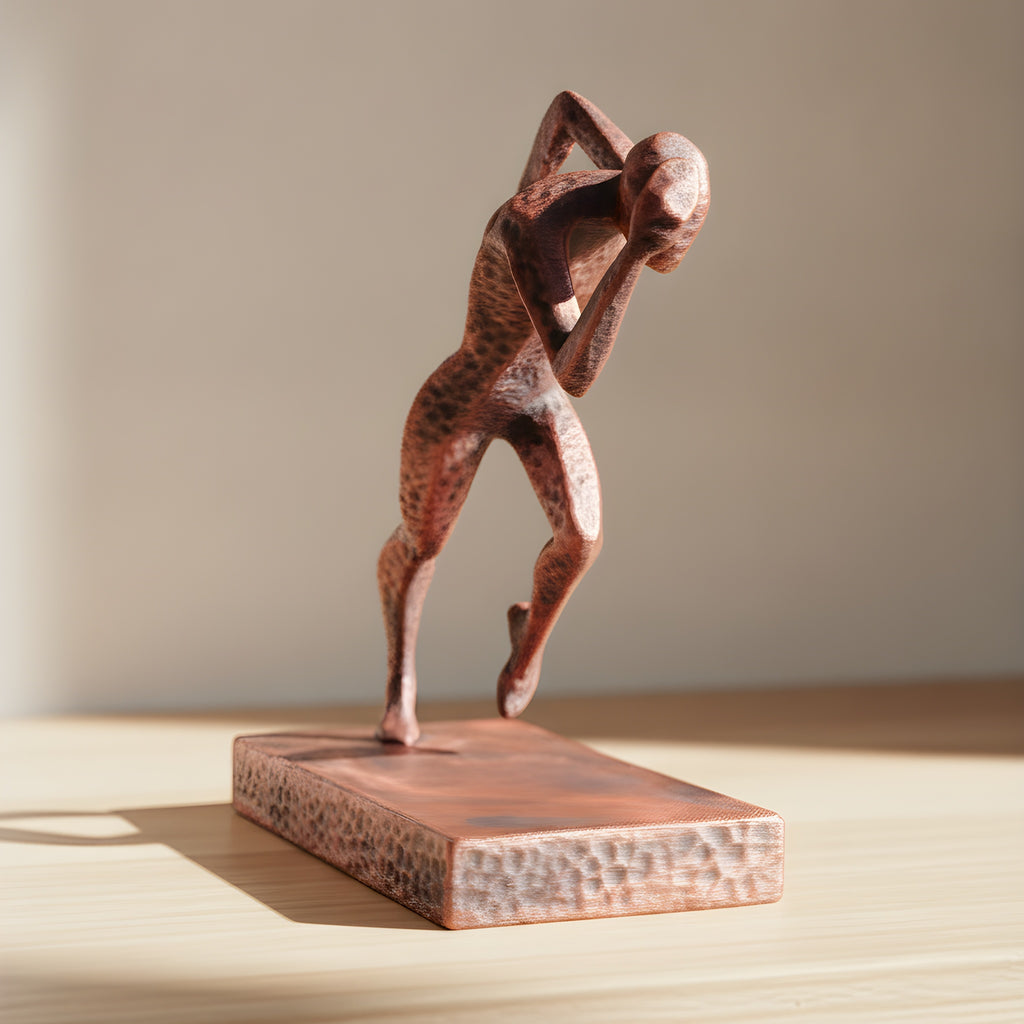 Detailansicht der nach vorne gebeugten Läufer-Statue in Kupfer-Bronze-Optik auf Holzoberfläche, weich unscharfer warmer Hintergrund – Münch3D