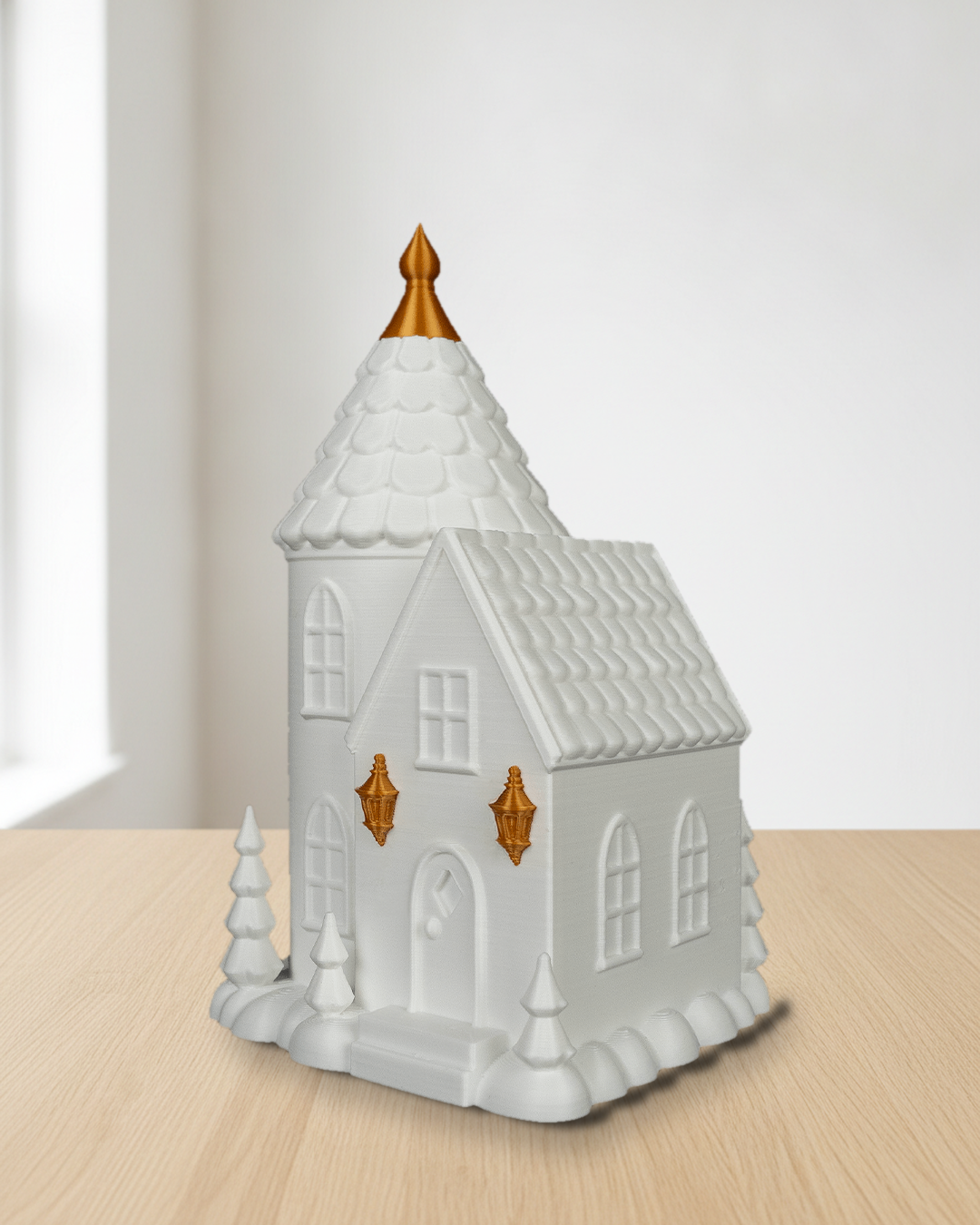 Turmhaus in Weiß mit goldener Spitze und goldenen Laternen, unbeleuchtet auf einem hellen Holztisch vor einer weißen Wand im Tageslicht