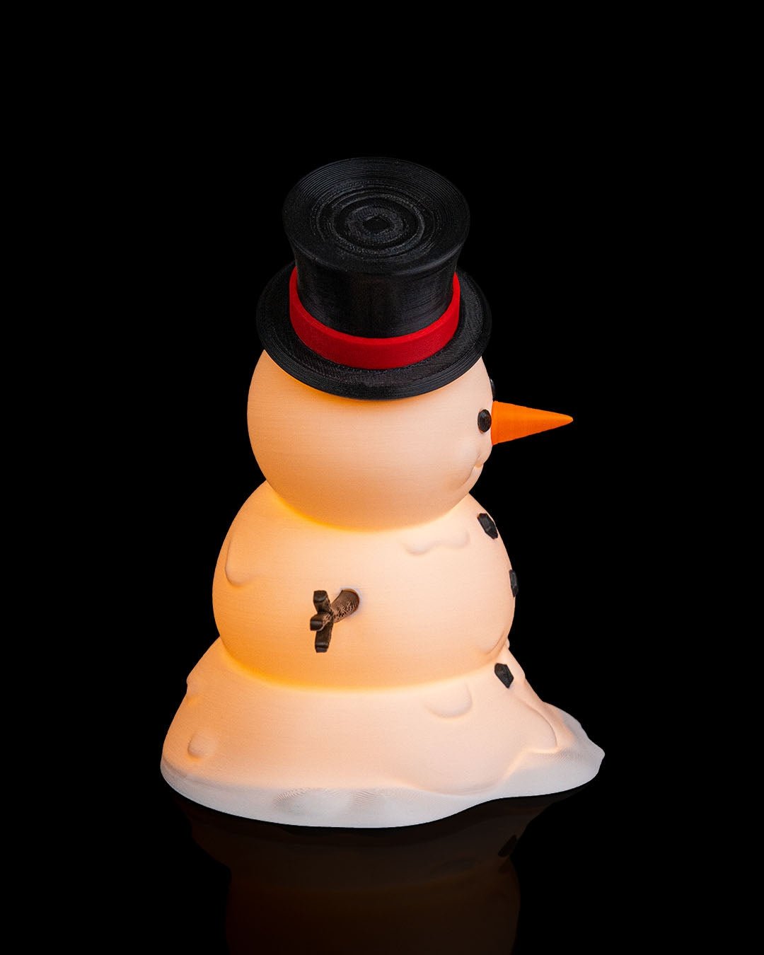 LED-Tischlampe Schneemann mit Zylinderhut, ausgestreckten Astarmen und Kohle-Knöpfen, Frontalansicht vor schwarzem Hintergrund