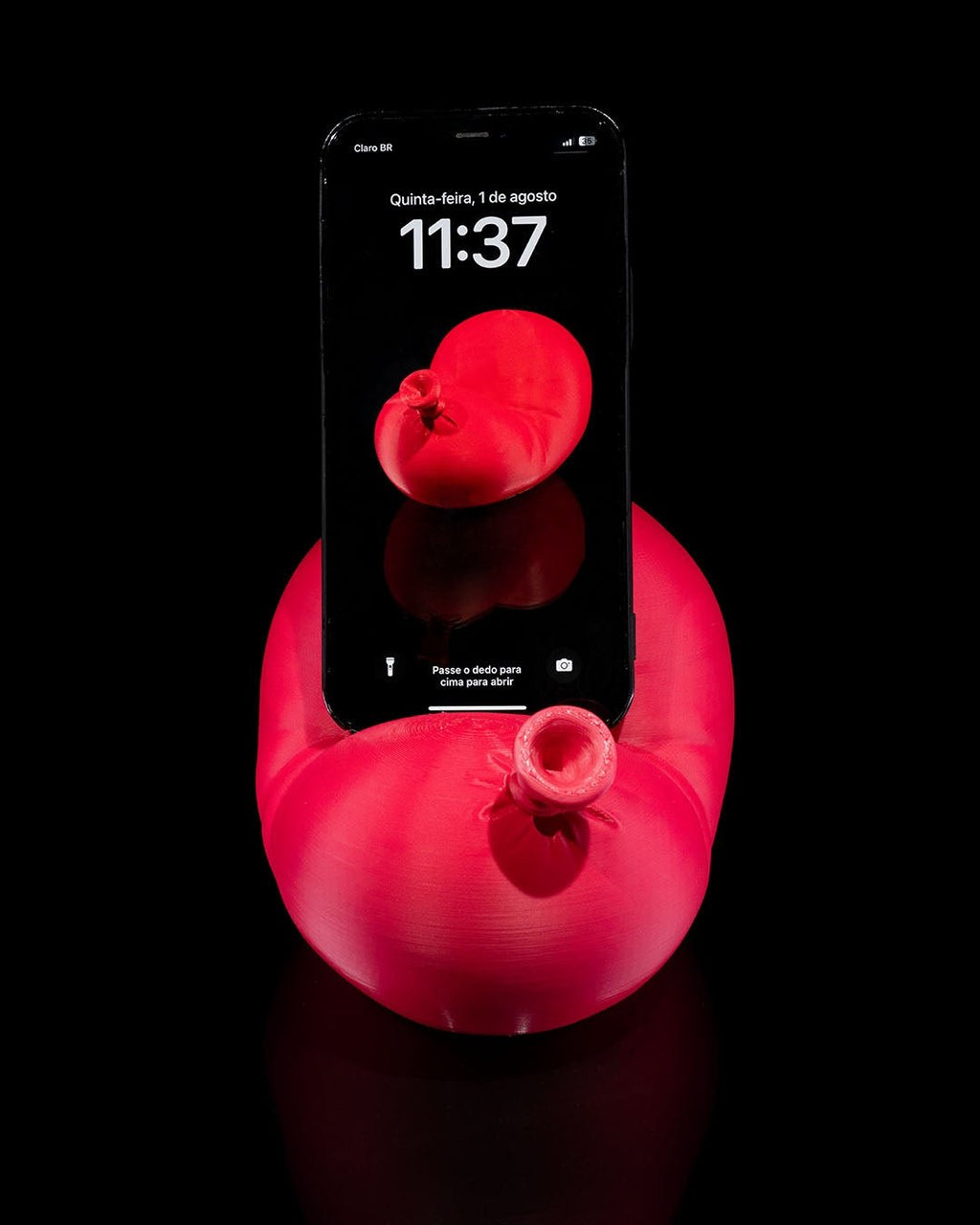 Roter Luftballon-Handyhalter mit eingestecktem Smartphone, Ansicht mit sichtbarem Ballonknoten, schwarzer Hintergrund