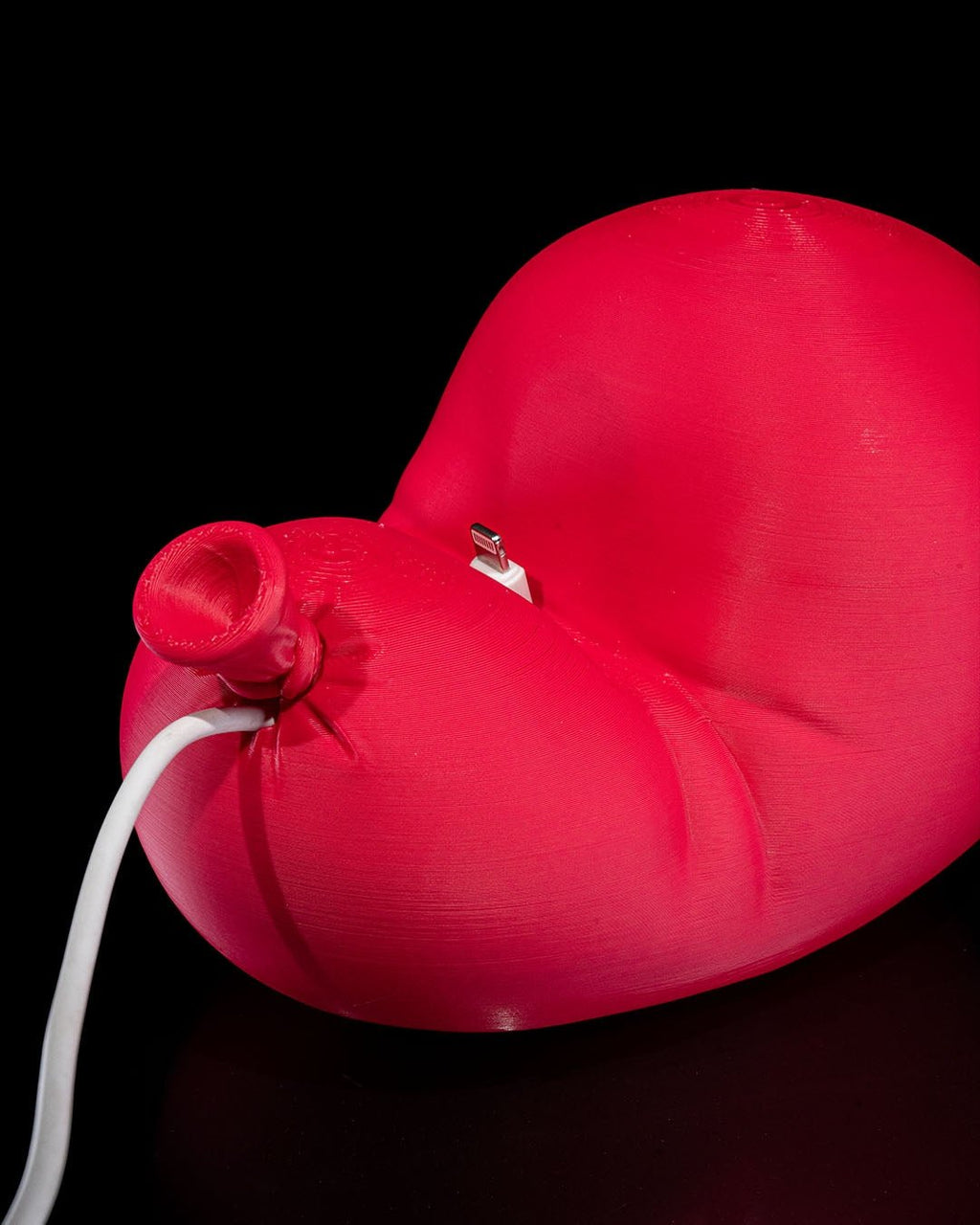 Roter Luftballon-Handyhalter mit eingestecktem Ladekabel am Ballonknoten, ohne Smartphone