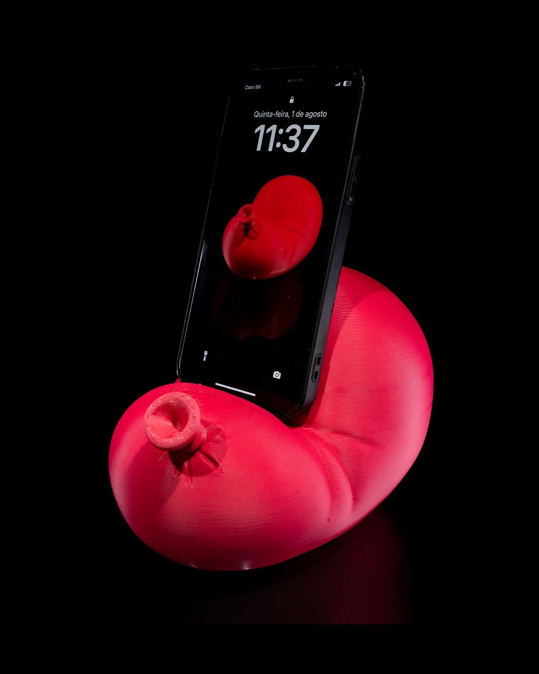 Roter Luftballon-Handyhalter mit eingestecktem Smartphone, Frontalansicht vor schwarzem Hintergrund
