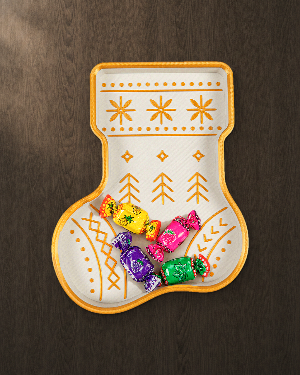 Nikolausstiefel-Schale in Weiß und Gold von oben auf dunklem Nussbaumholz, gefüllt mit vier bunt verpackten Bonbons