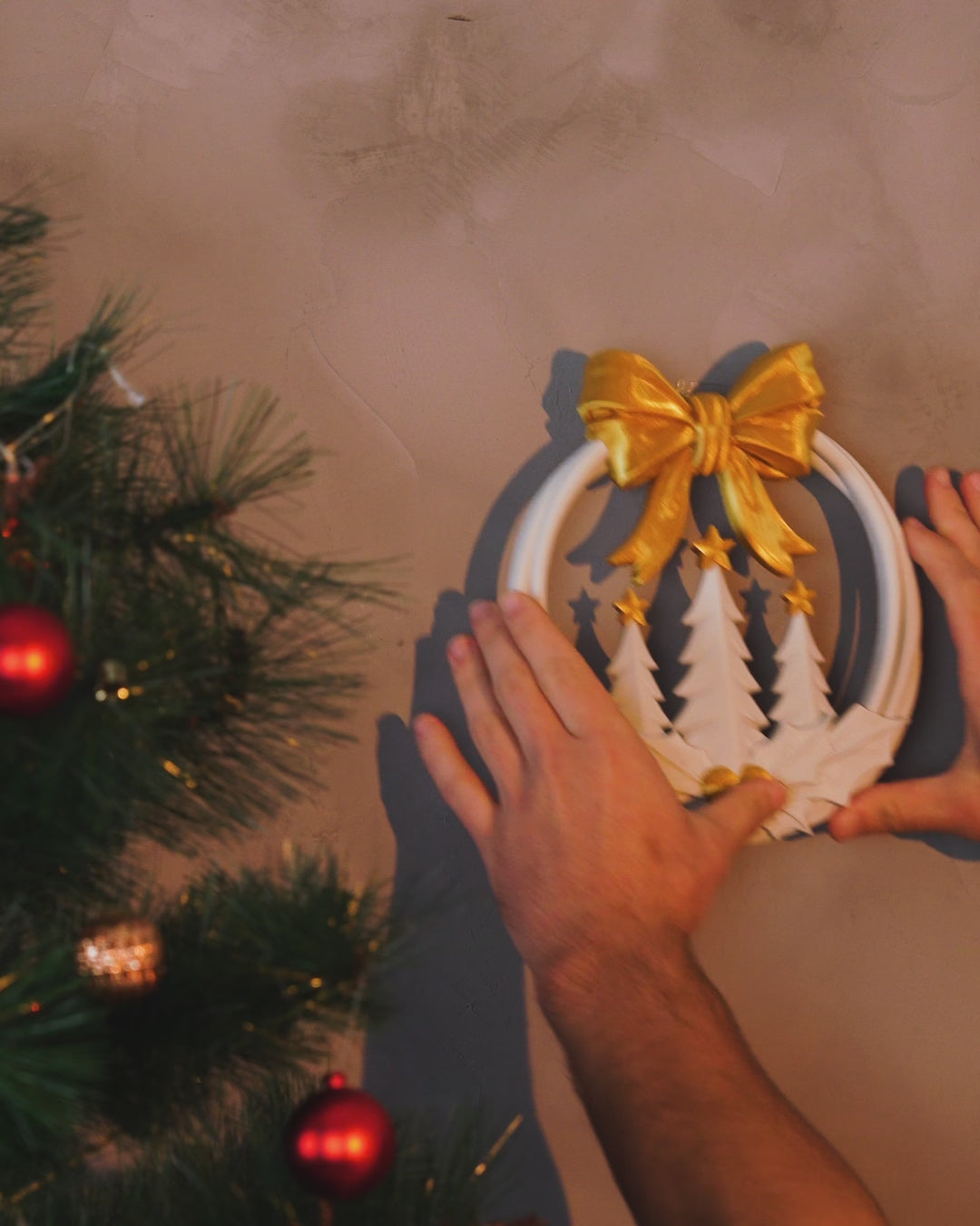 Kurzvideo: Weihnachtskranz in Weiß und Gold mit goldener Schleife, Tannenbäumen und Stechpalme wird an die Wand gedrückt