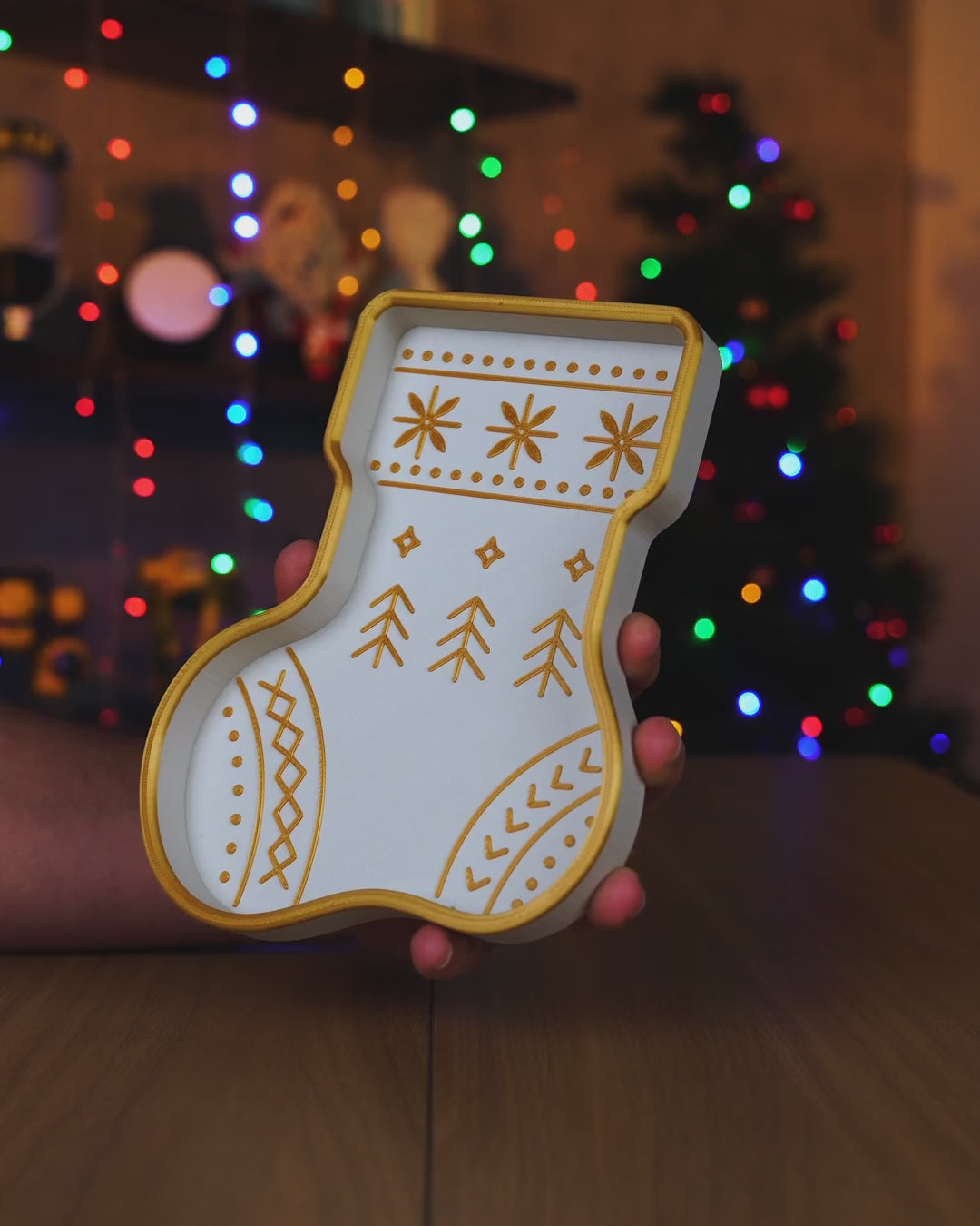Kurzvideo: Weiß-goldene Nikolausstiefel-Schale wird in der Hand gedreht, im Hintergrund leuchten Weihnachtsbaum-Lichter